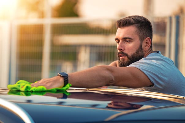 Young man cleaning his car outside